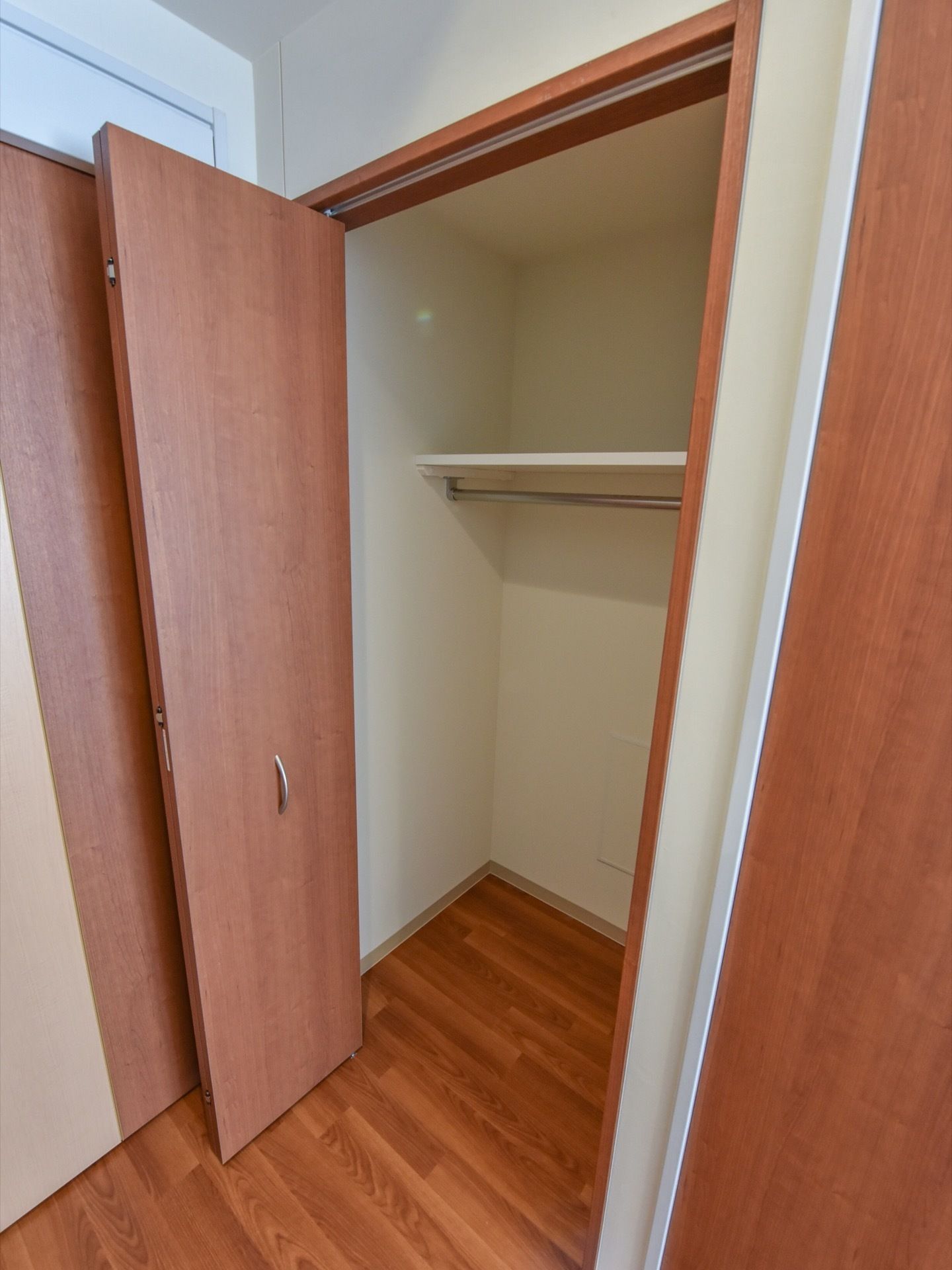 部屋に備え付けられた収納。足元には段差がなく、扉は大きく開く。ハンガーラックの上には、棚が設置されている。