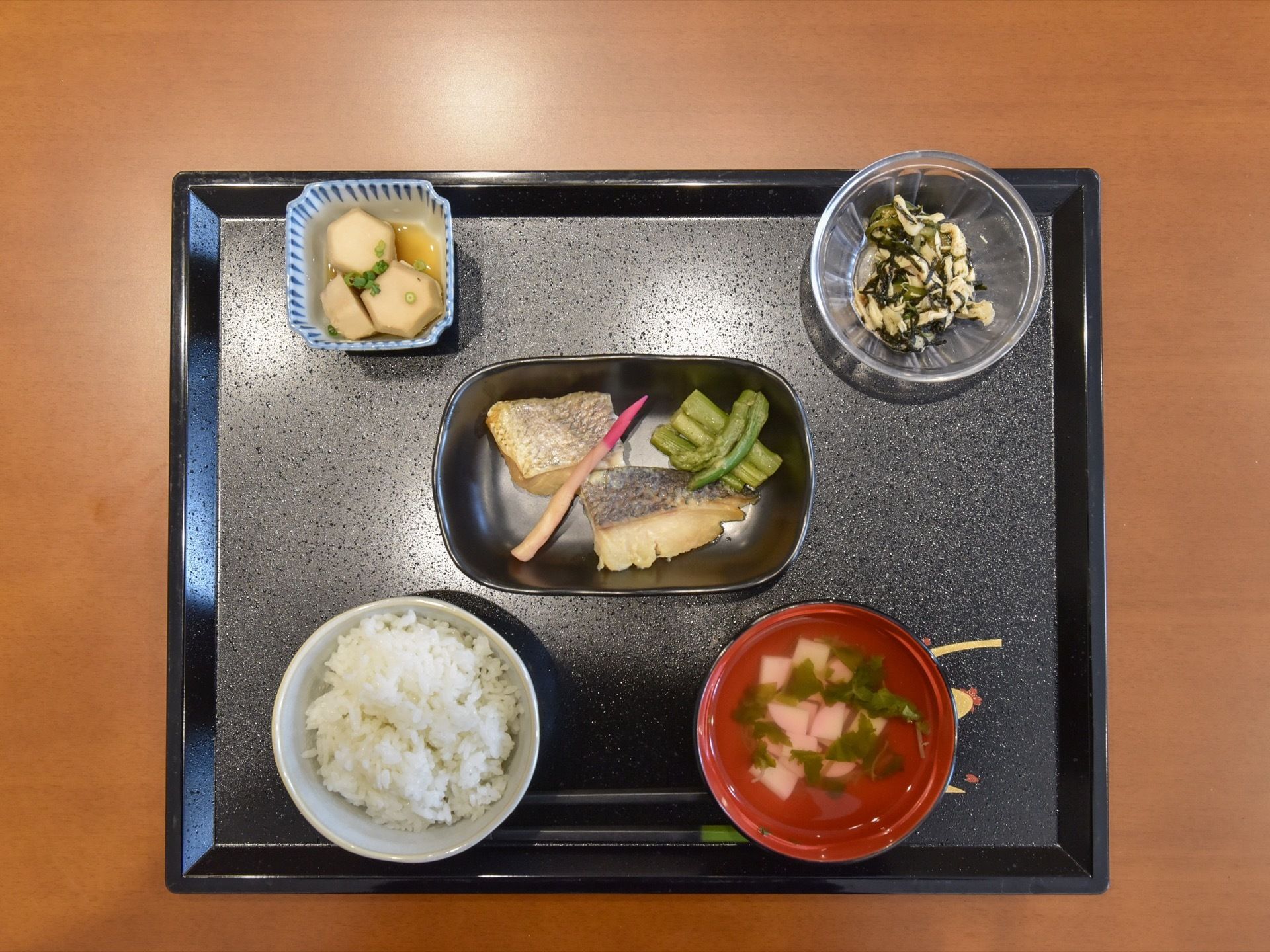 お魚と野菜が添えられたお皿に、里芋の煮物、小鉢が１つ、お吸い物にご飯が本日のメニューである。綺麗なお盆の上にのせられている。