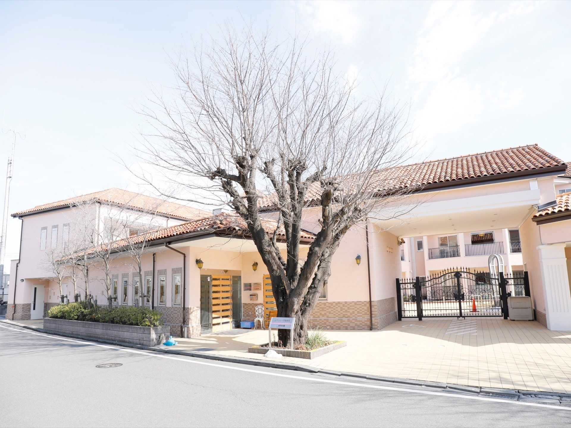 敷地の前は、広い整備された遊歩道になっている。大きな木の前には、施設名が入ったプレートが置かれている。