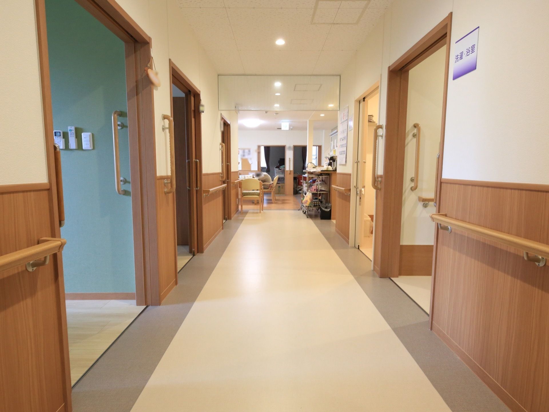 廊下の左右には、浴室や居室などの扉が並んでいる。直線の廊下なので正面に広がる共有のダイニングスペースが良く見える。