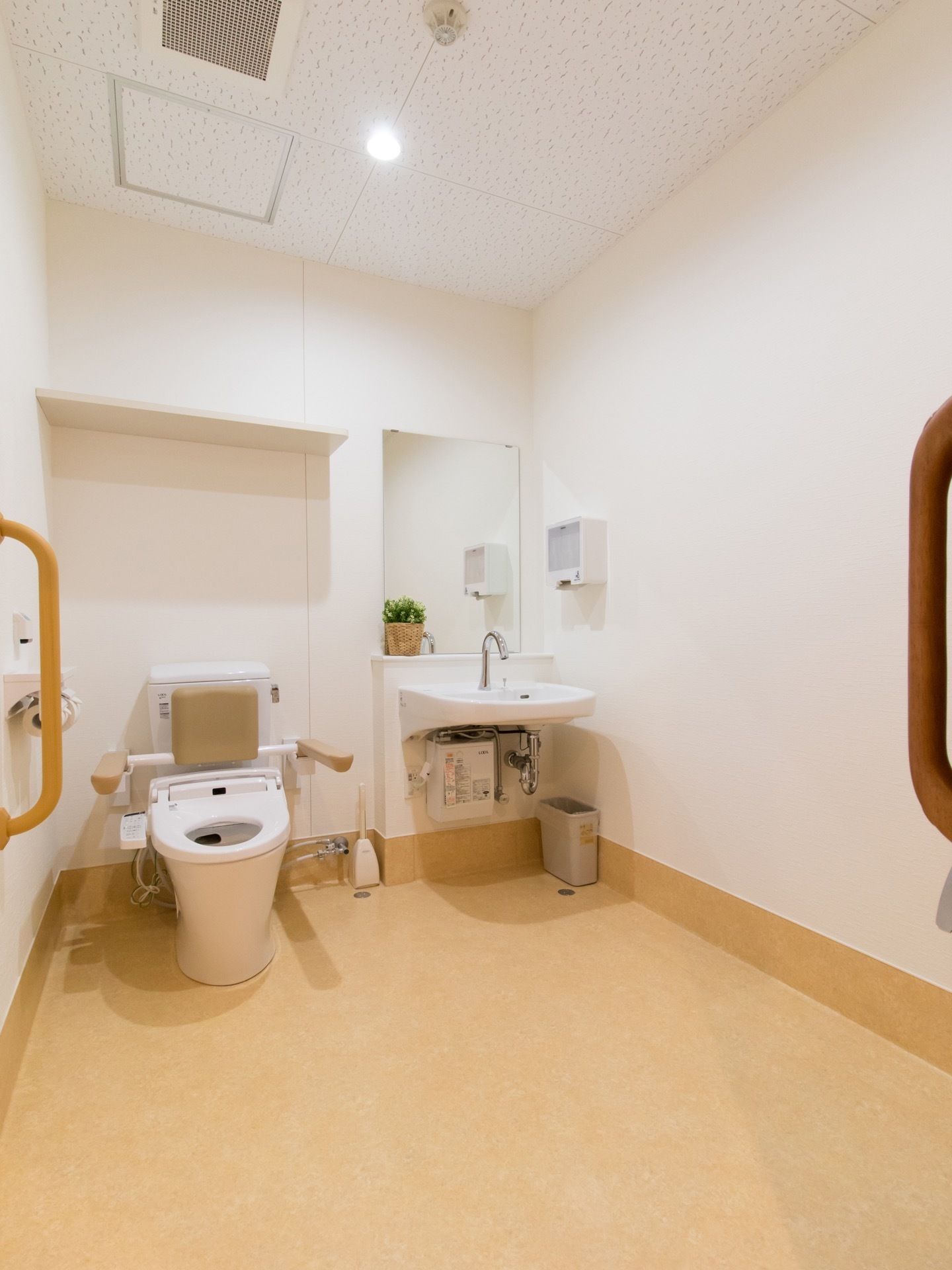 温水洗浄便座付きの洋式トイレには手すりなどが付いている。隣に設置されて洗面台の足元には収納などがないので、車椅子のまま使用することができる。
