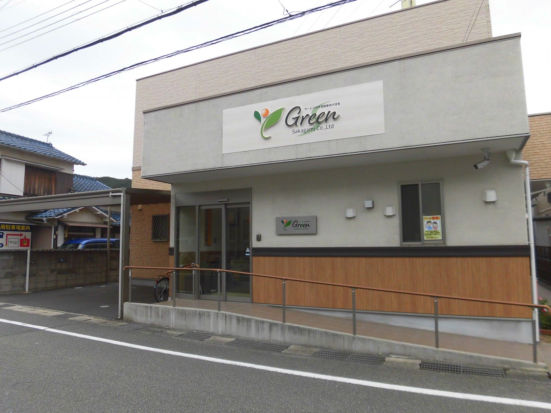 白とベージュで統一された２階建ての建物である。エントランスまでは、手すりの付いた緩やかなスロープが完備されている。