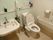 共用トイレは広いスペースが確保されており、洗面台も備わっている。立ち座りの動作を助ける可動式の手すりが設置されている。