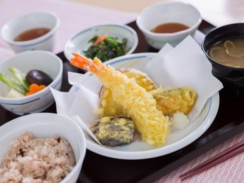 お赤飯や天ぷら、お味噌汁などが彩りよく盛り付けられているトレー