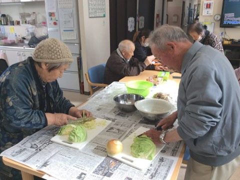 共有スペースのテーブルの上でキャベツを千切りにしているご入居様