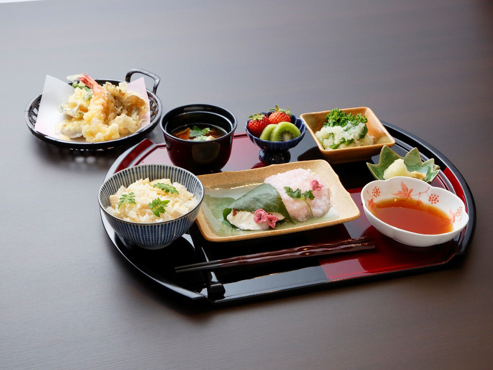 松花堂弁当のような器に美しく盛り付けられた手の込んだお料理。後方には、カップに入った料理もある。食べやすい大きさに配慮されている。