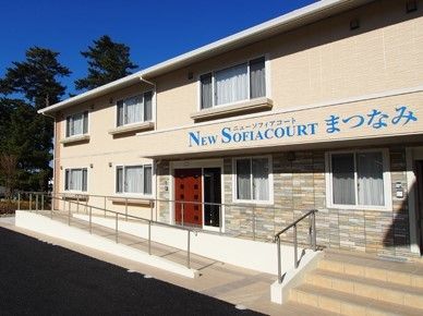 エントランスまで手すり付きのスロープが続いている、レンガのアクセントがおしゃれな建物