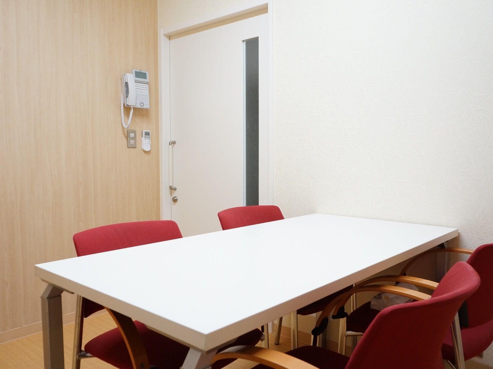 談話室には、白テーブルと赤い椅子があり、椅子には肘掛けが備えられているため、立ち座りの際に利用することができる。