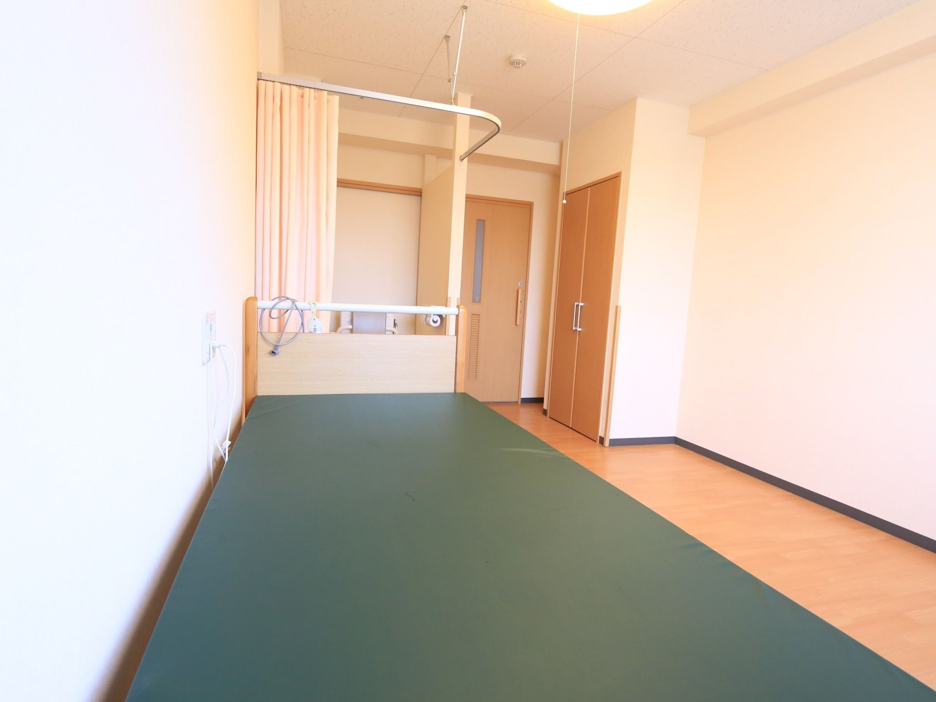 入居者様一人一人に割り当てられる居室。玄関ドアの近くには、カーテンで仕切られたトイレが設置されている。