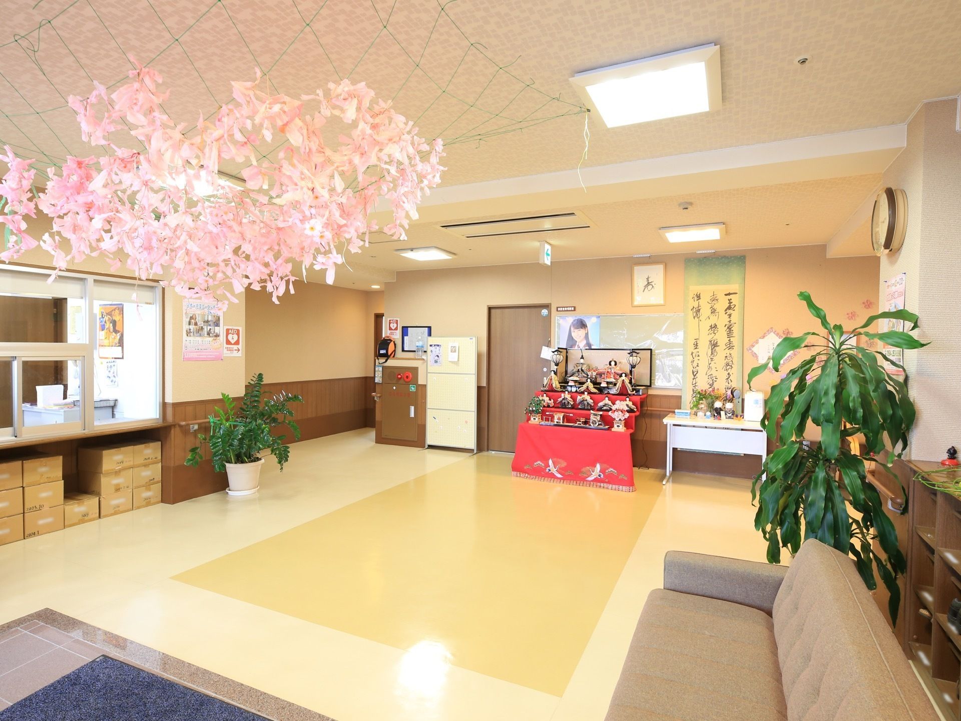 ホールの天井にはピンク色の折り紙で製作した装飾品を設置している。入居者様は明るい雰囲気の中を通行することができる。