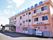 淡いピンク系の３階建ての建物である。エントランスには大きな屋根が完備されている。周辺はアスファルトで舗装されている。