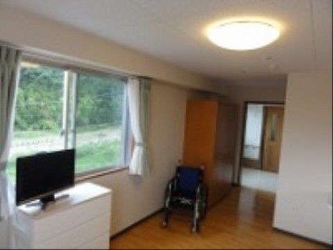 廊下とは段差のないフラットな床となっており、窓からは豊かな自然を眺めることができる。室内には車椅子が置かれている。