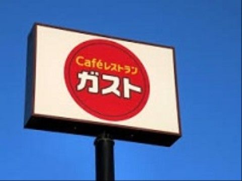 ファミリーレストランの看板の写真である。白を基調とした四角い看板に赤色の丸い円が描かれており、中に施設名が書かれている。