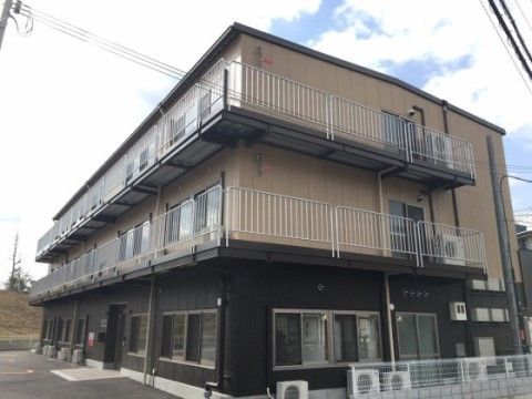 深みのあるブラウンで落ち着いた印象の、バリアフリー仕様のエントランスがある建物