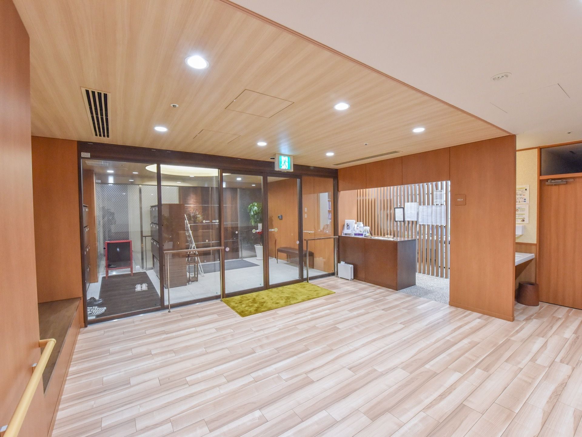 施設の受付が、玄関ホールの右端に設けられている。こげ茶色のカウンターの後方には、書類のようなものが貼ってある。