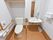 清潔感のあるトイレで、壁には木目調の手すりが付いている。側には洗面台が設置されており、大きな鏡もある。