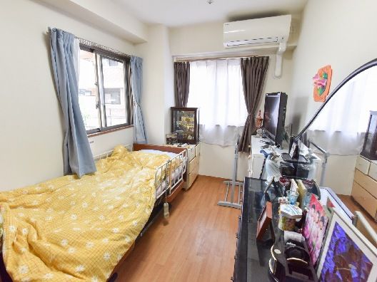 エアコンが付いたフローリングの部屋には寝具付きのベッドが置かれ、私物が持ち込まれている。