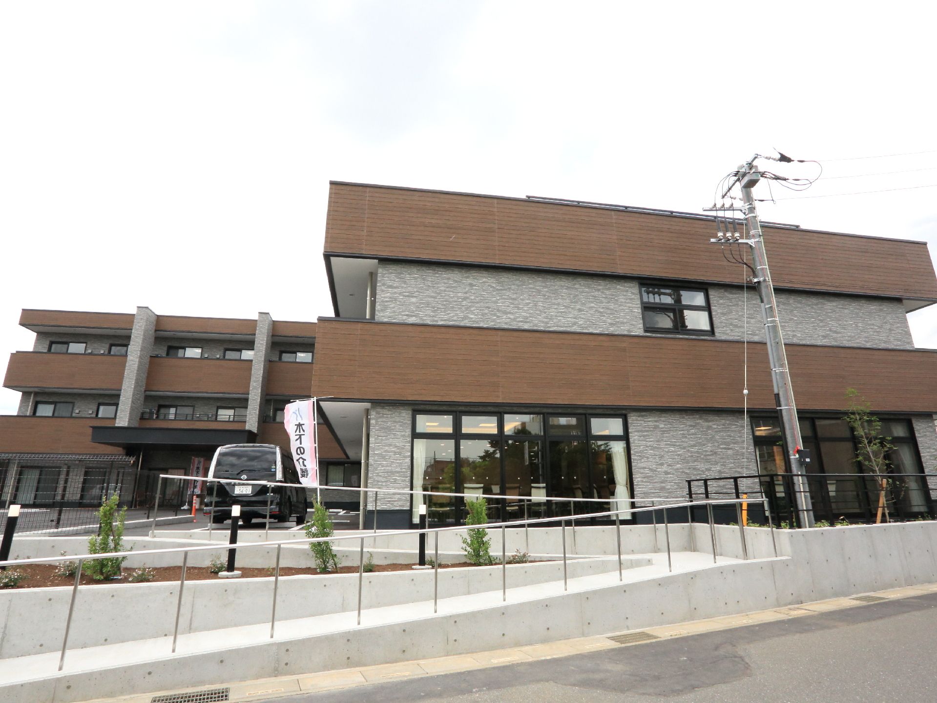 エントランスまで手すり付きのスロープが続いている、落ち着いた雰囲気の外観をしている建物