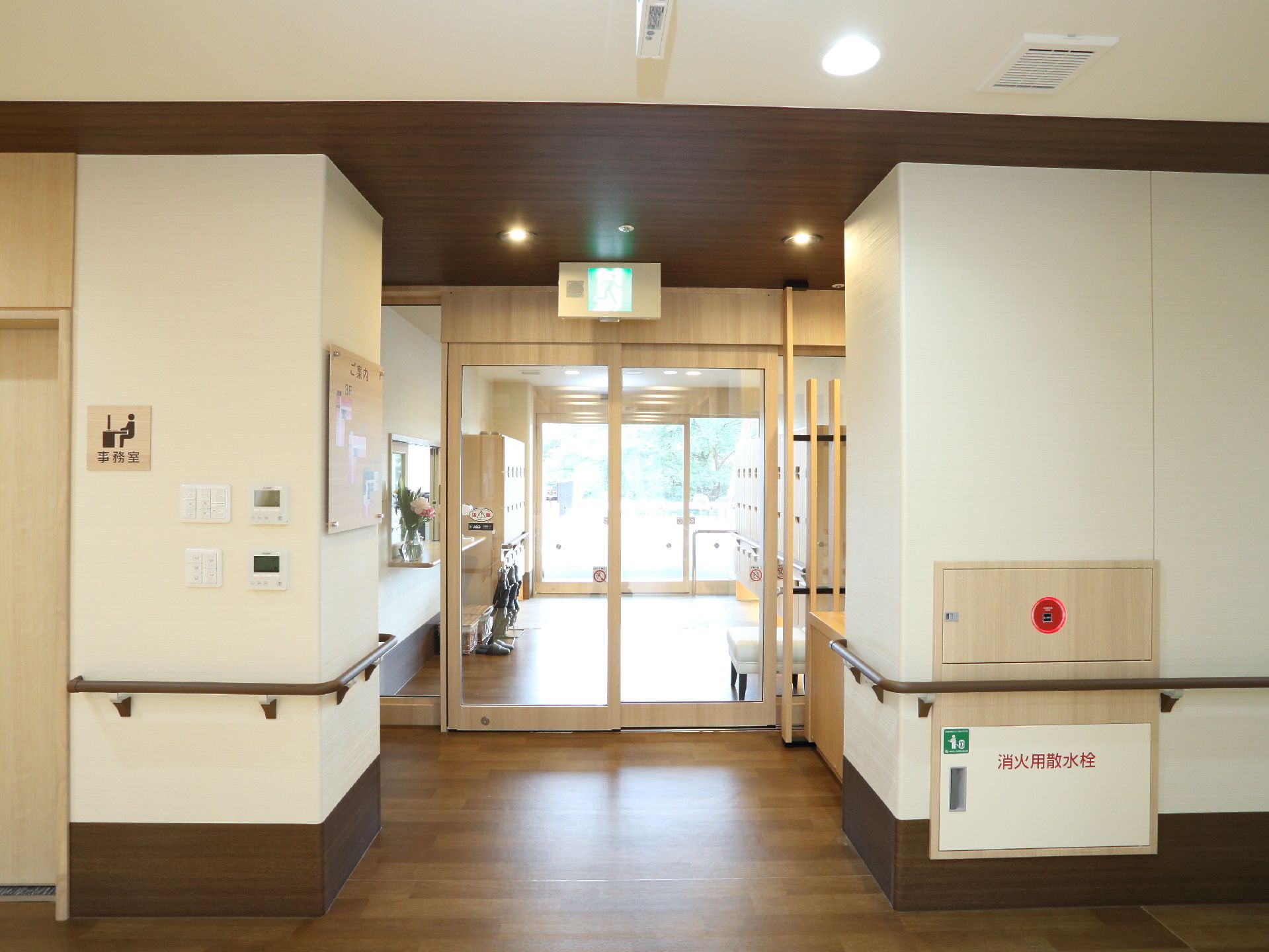 大きな自動ドア設けられたエントランスである。こちらのドアは避難経路にもなっている。ドアの向こうには、受付がある。