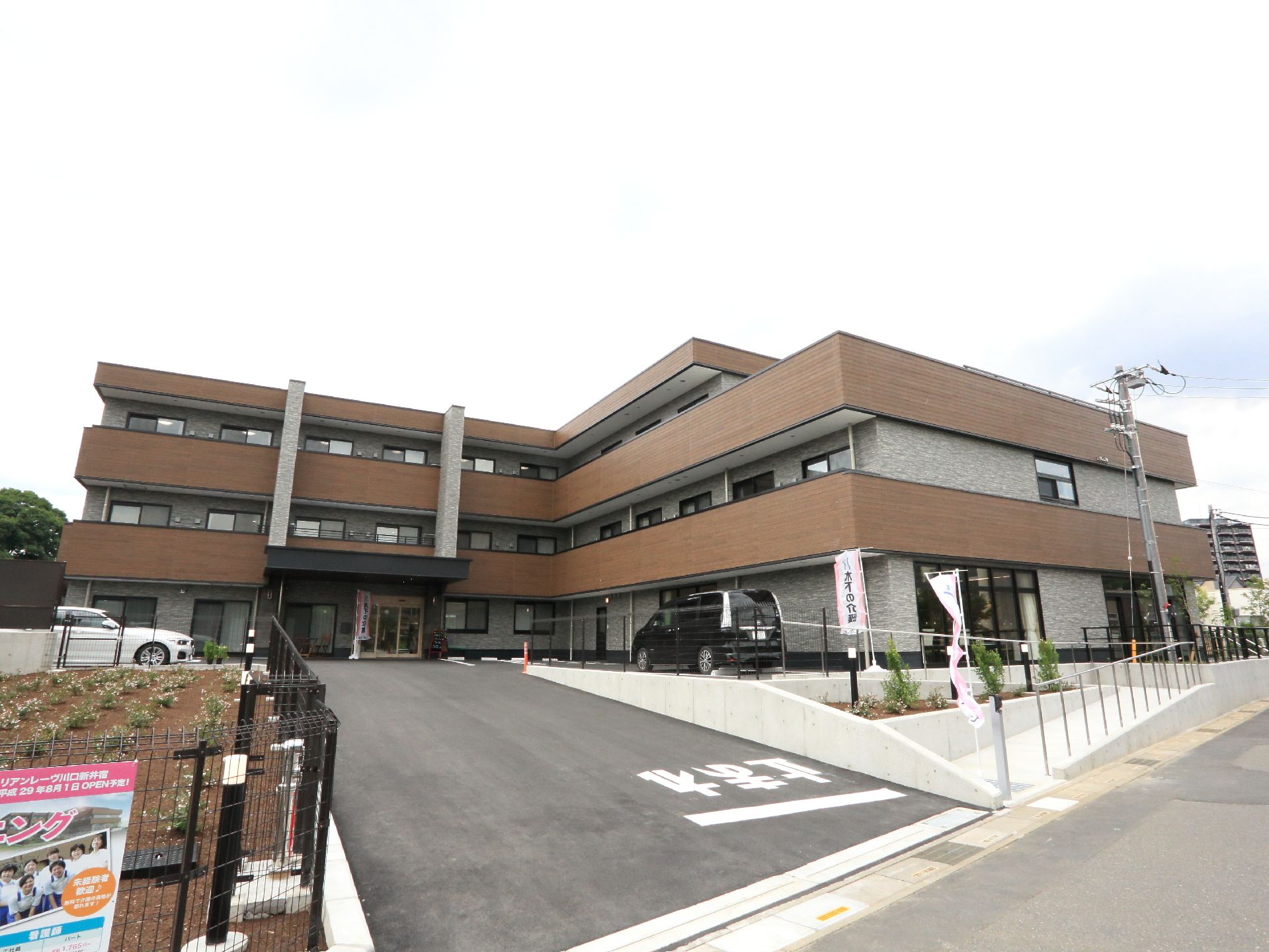 2台の車が同時に出入りできる幅広い出入口。出口側の路面には、止まれの表示がある。建物の前の敷地は、広々としている。