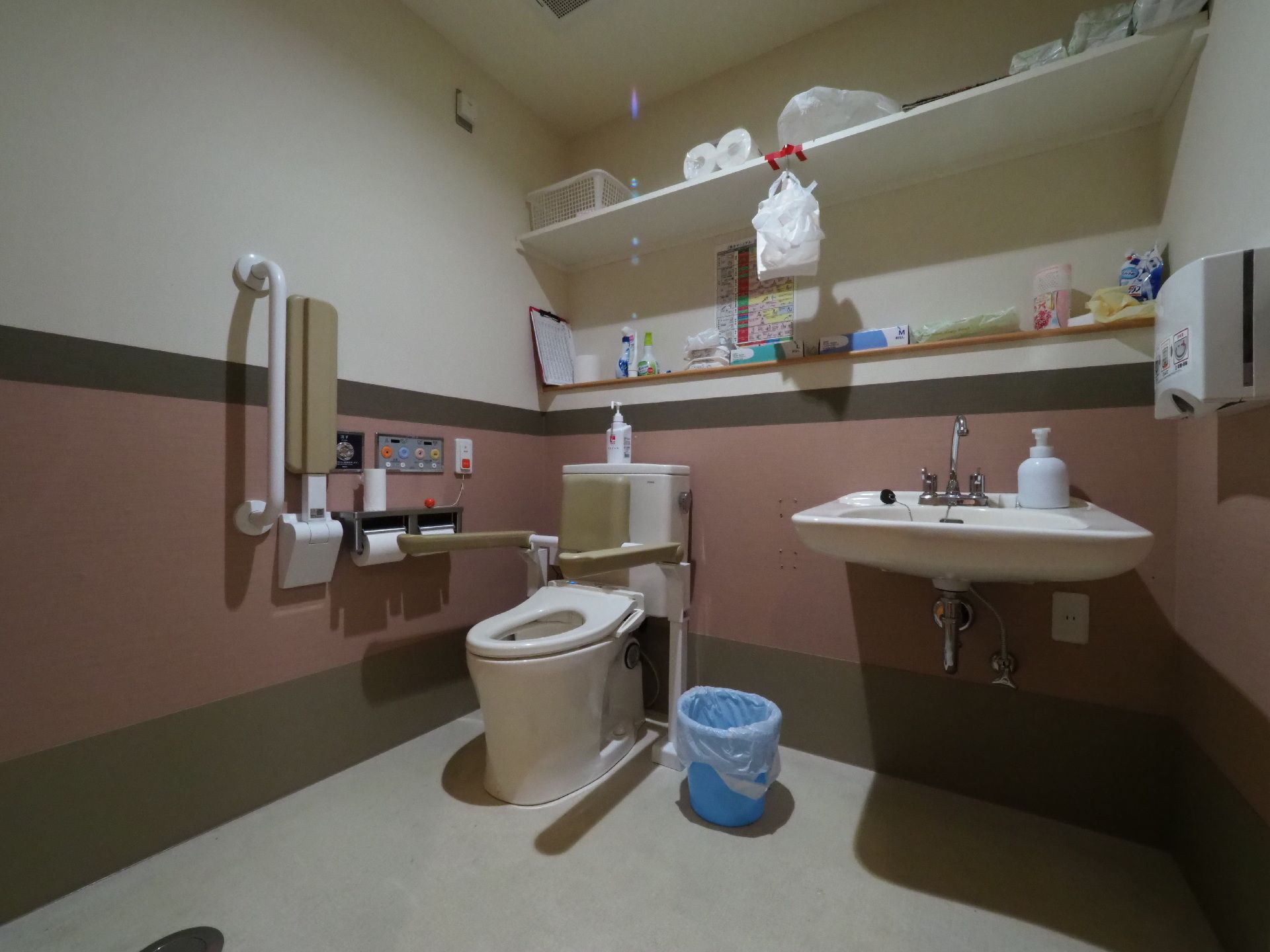 広いスペースが確保された温水洗浄便座付きのトイレである。便器に固定タイプや壁に取り付けタイプの手すりが設置されている。