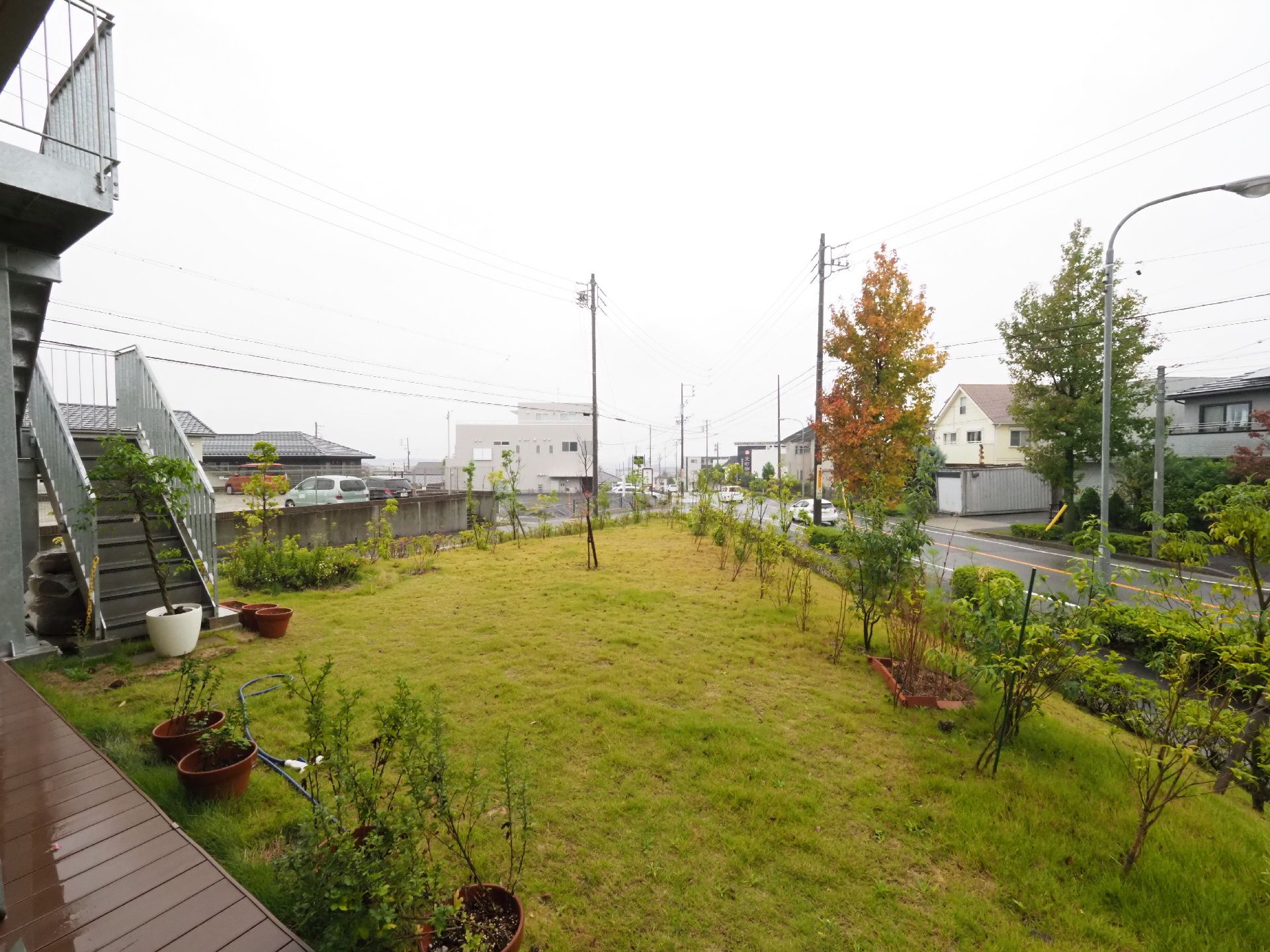 施設の裏には、木が植えられている芝生の庭がある。プランターが置かれている。非常階段が設置されている。