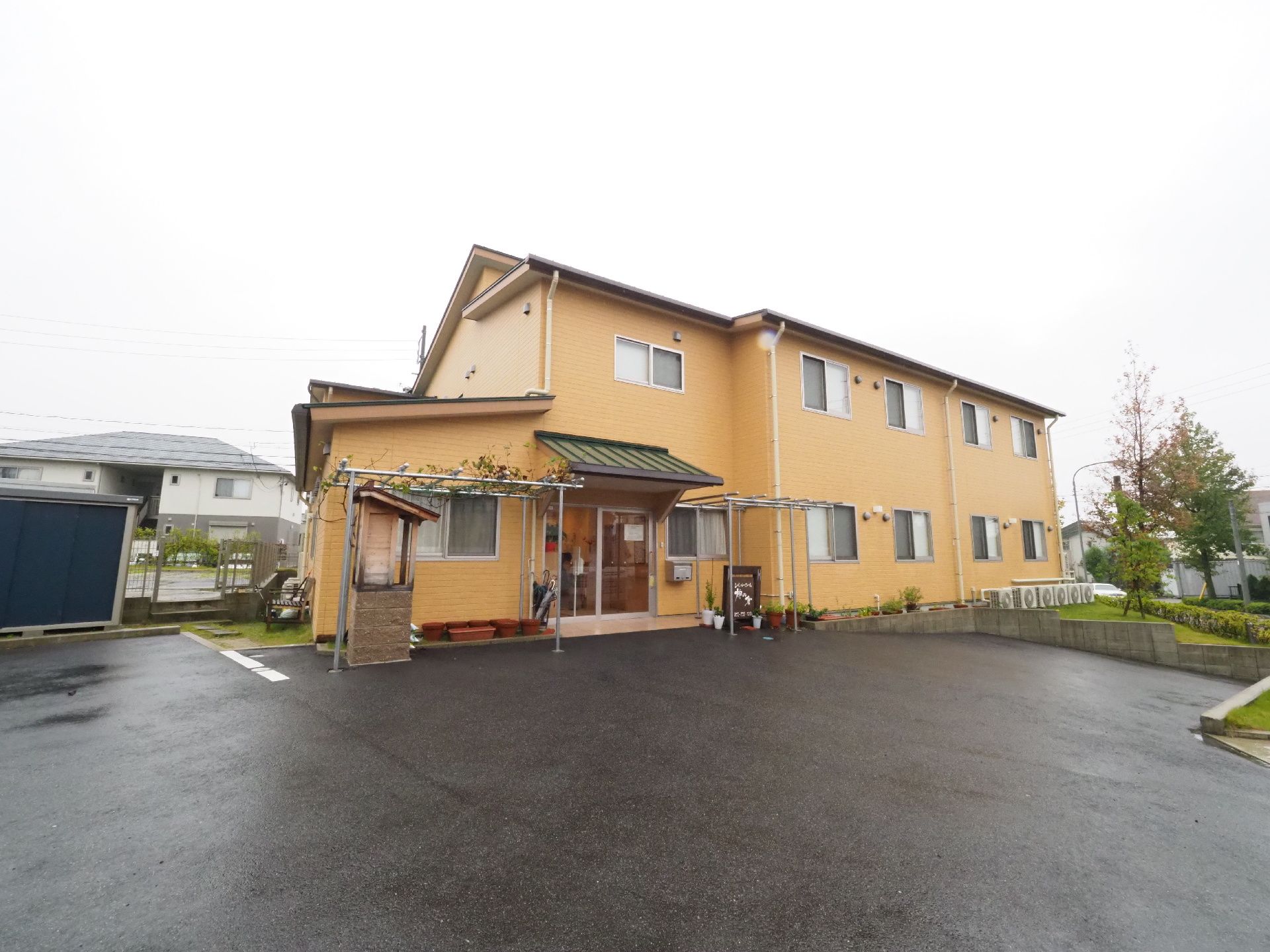 施設はクリーム色の2階建ての建物である。1階に入口があり、入口の部分には屋根がついている。施設の前には広い駐車場がある。