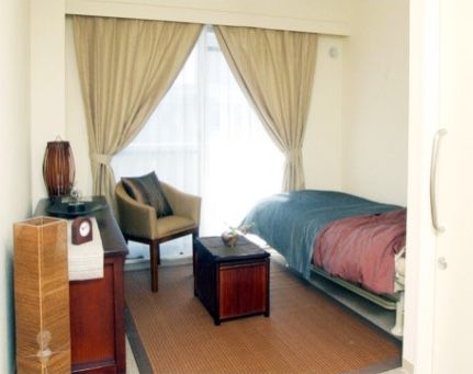 大きな窓にカーテンがかかり、ベッド、椅子、収納などがある部屋