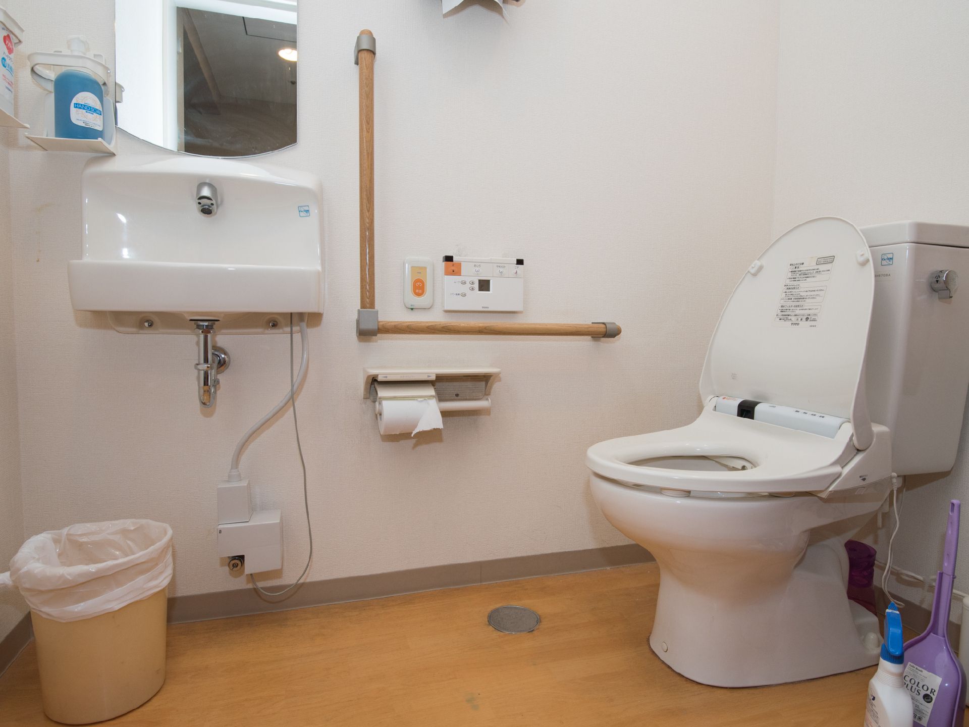 トイレは洋式で、手すりが設置されている。流したりシャワー機能を使う時のリモコンスイッチと、緊急時の呼び出しボタンが右手側にある。