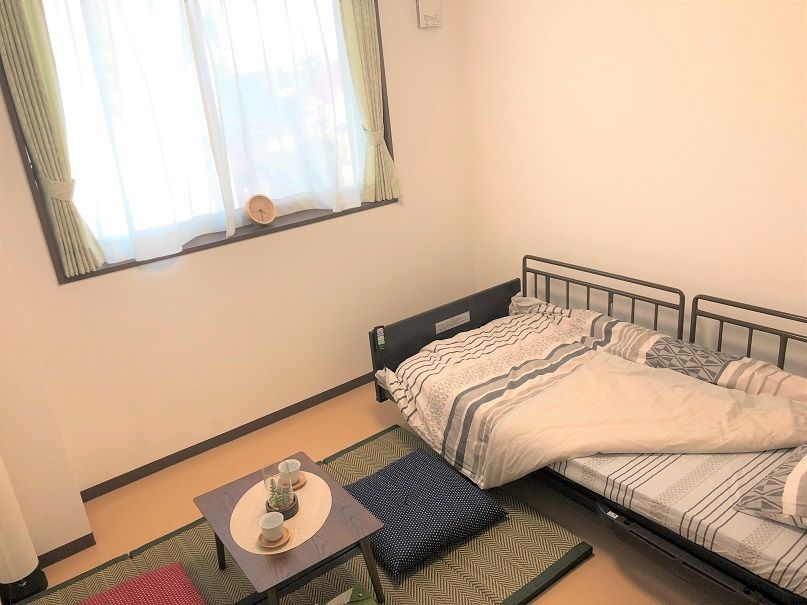 い草のマットや座布団が敷かれた和風の居室にはベッドが置かれ、ブルー系の布団がセットされている。