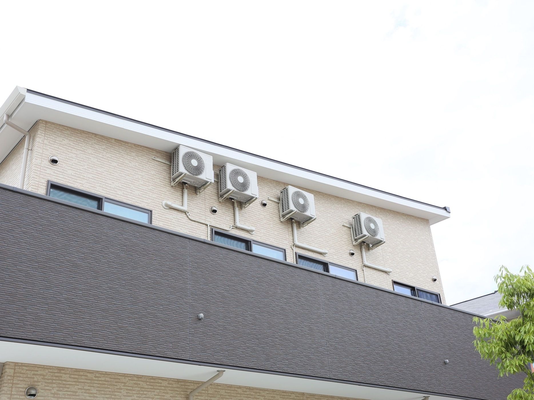 二階部分の壁に取り付けられた複数の室外機。各居室にエアコンを設置してあり、壁のパイプはそこにつながっている。