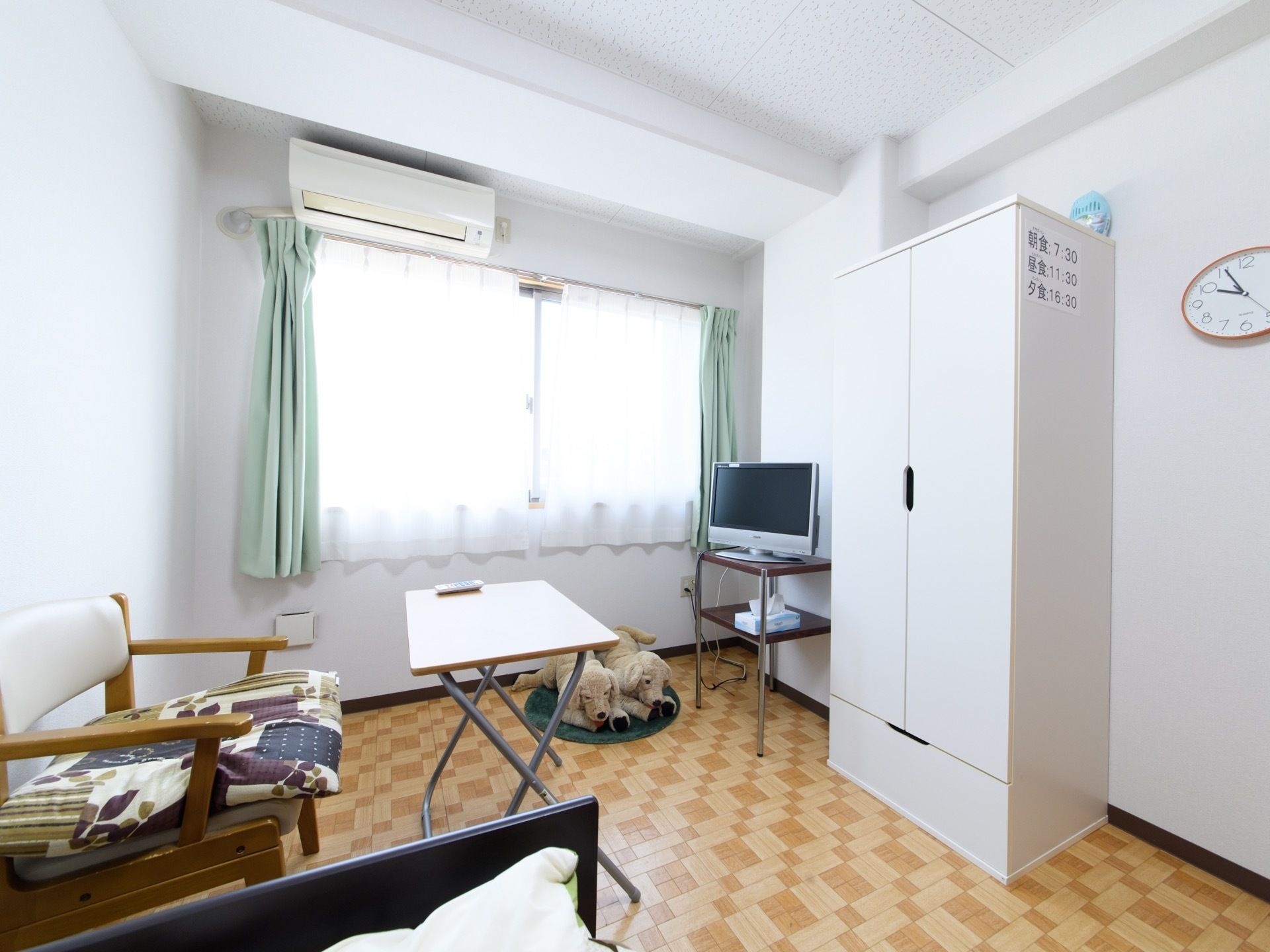椅子が置いてある。犬のぬいぐるみが２つ床にある。収納ボックスが設置されている。エアコンが取り付けられている。