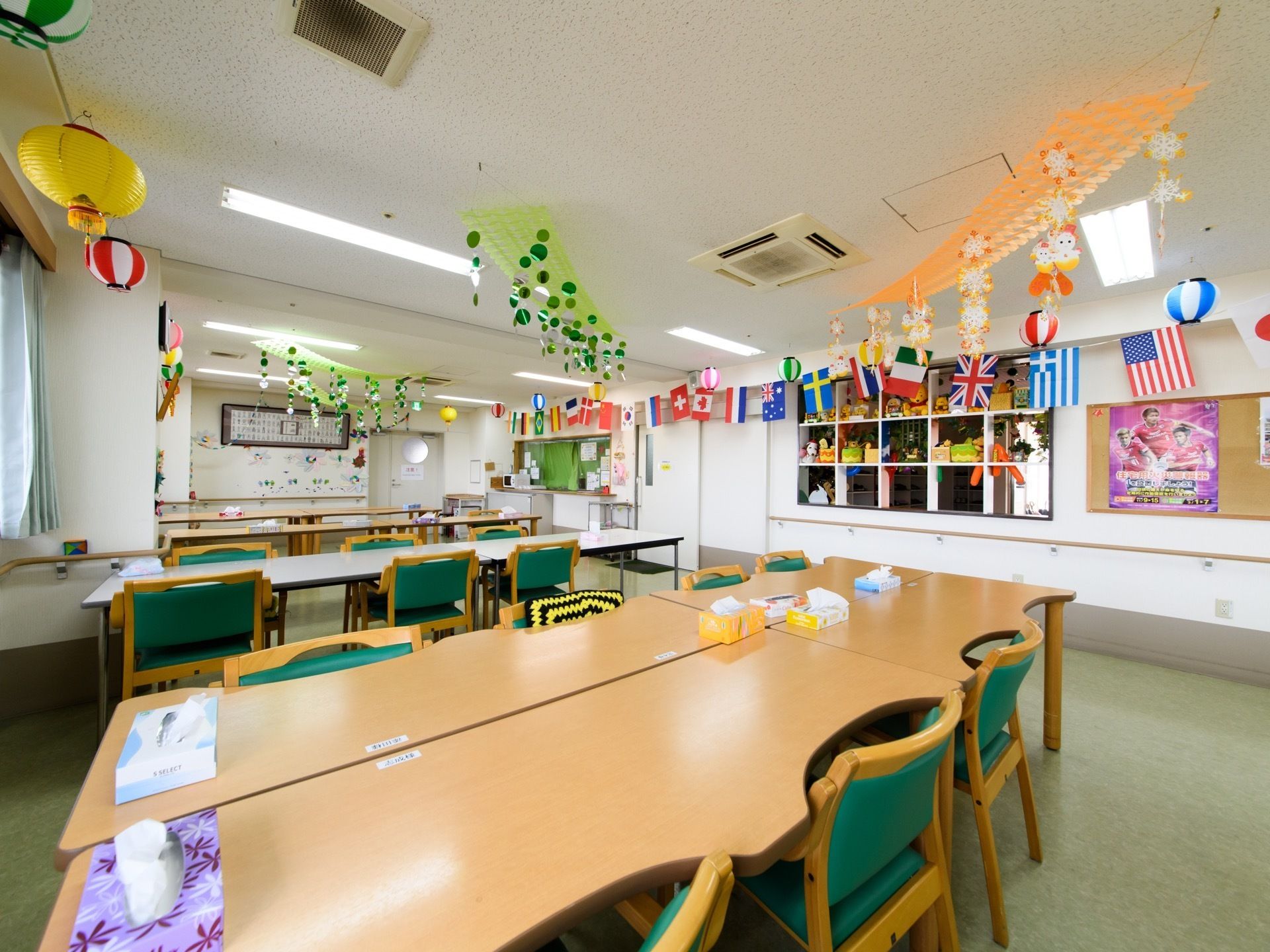 テーブルと椅子が並んでいる。天井には万国旗などのたくさんの飾り付けがされている。壁には手すりが取り付けられている。
