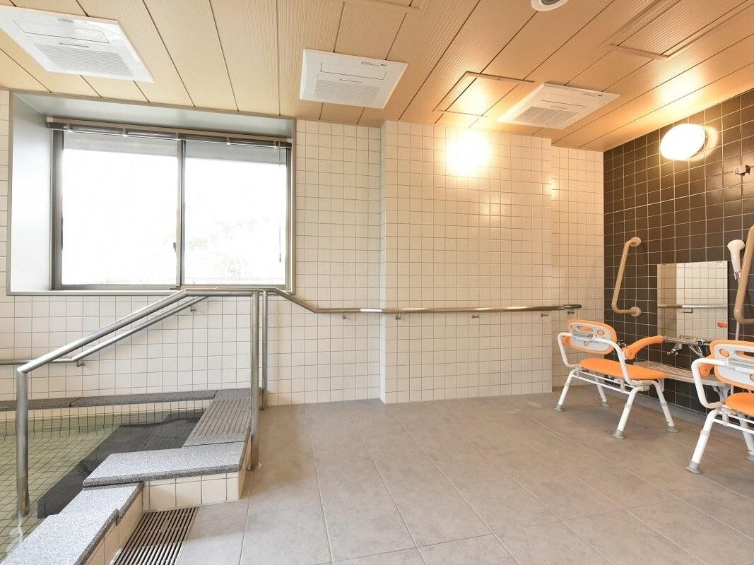 浴室は温泉風の構造で、壁はタイルを使用し浴槽は石材を用いている。手すりや緑が見える窓が取り付けられている。