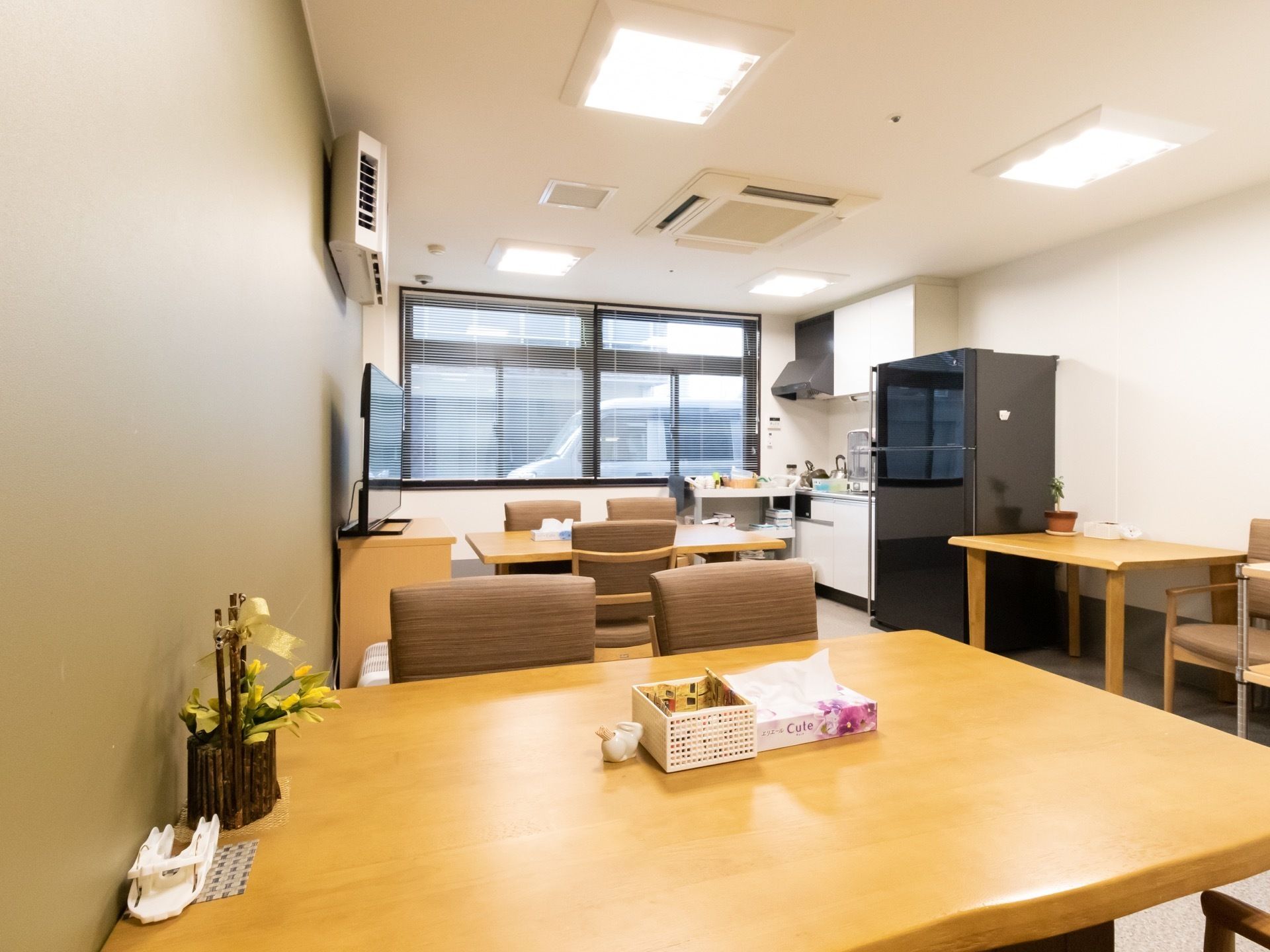 テーブルと椅子がたくさん並んでいる食堂がある。突き当りは窓になっており、キッチンと冷蔵庫が置かれている。
