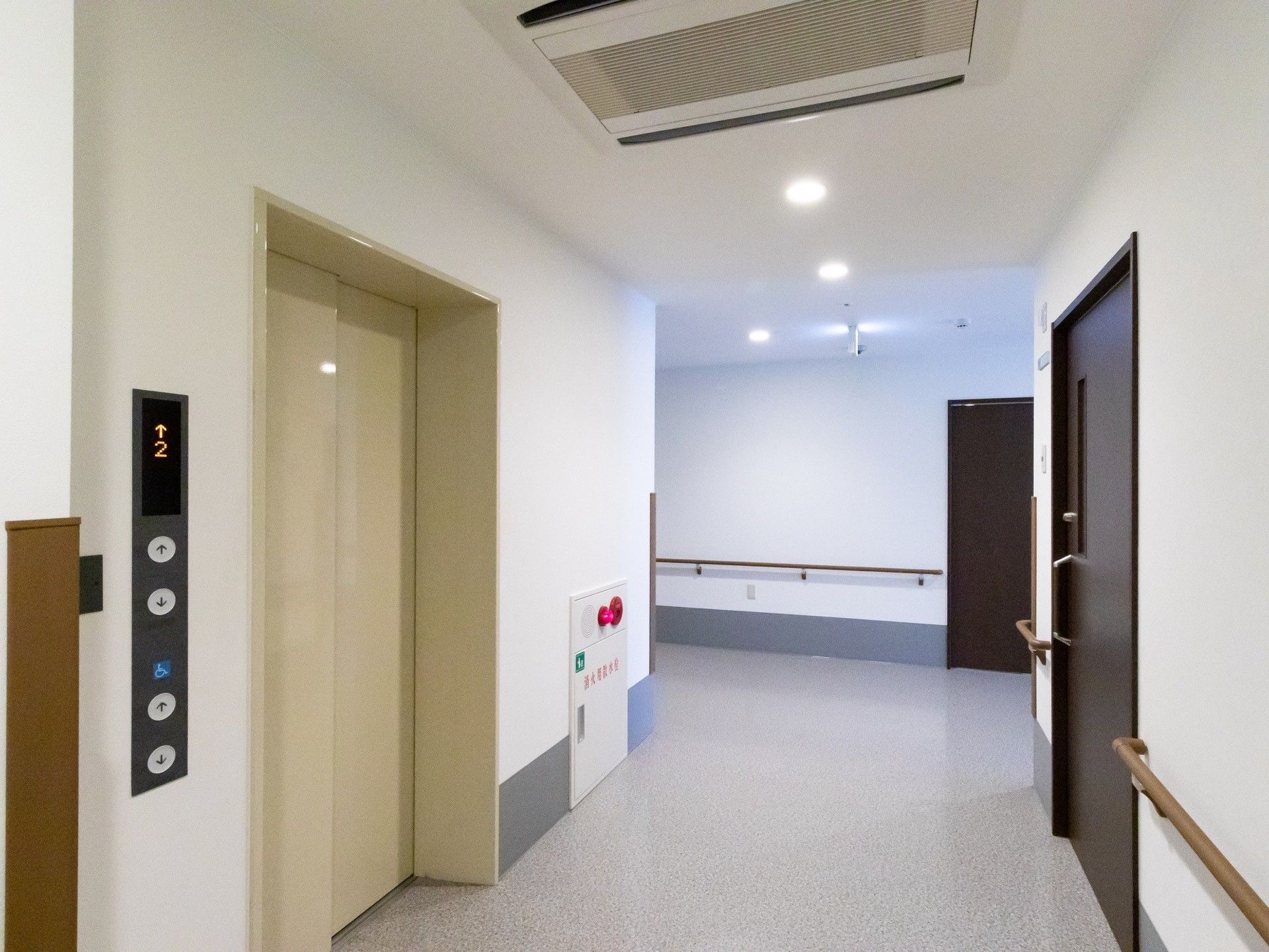 壁伝いに手すりが設けられた、広い通路である。ホワイト調のエレベーターが完備されている