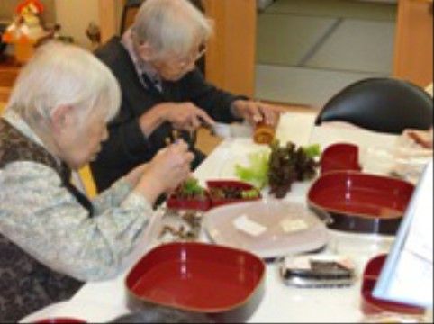 共有スペースで野菜などを容器に詰める高齢者のお二人