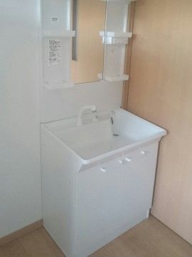 部屋の隅にはきれいに清掃された白色の洗面台がある。洗面台の下には収納スペースもあり、洗面用品を片付けることができる。