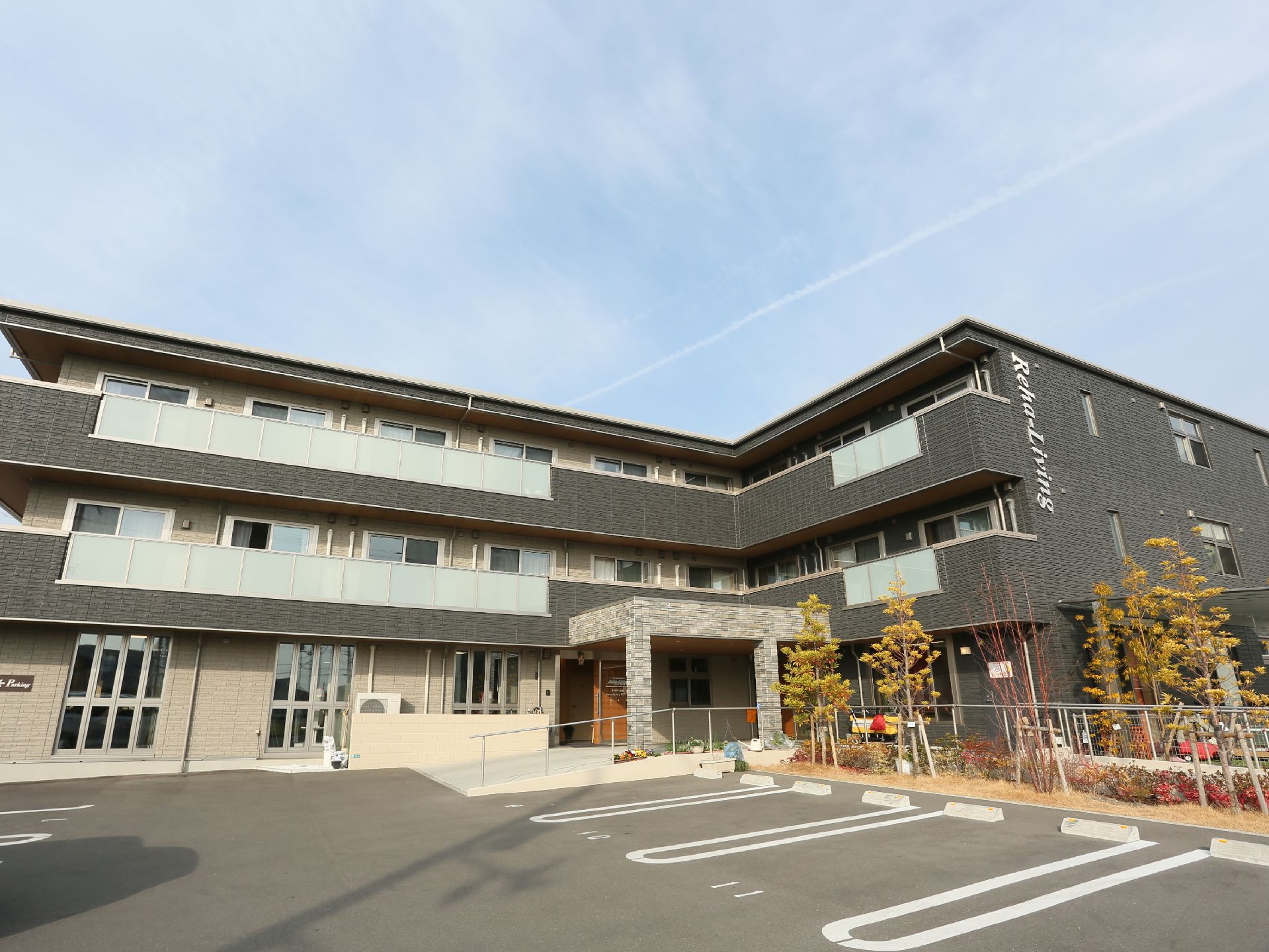 ３階建てのサービス付き高齢者向け住宅である。建物前に駐車場が設けられており、手すり付きのスロープがエントランスに設置されている。