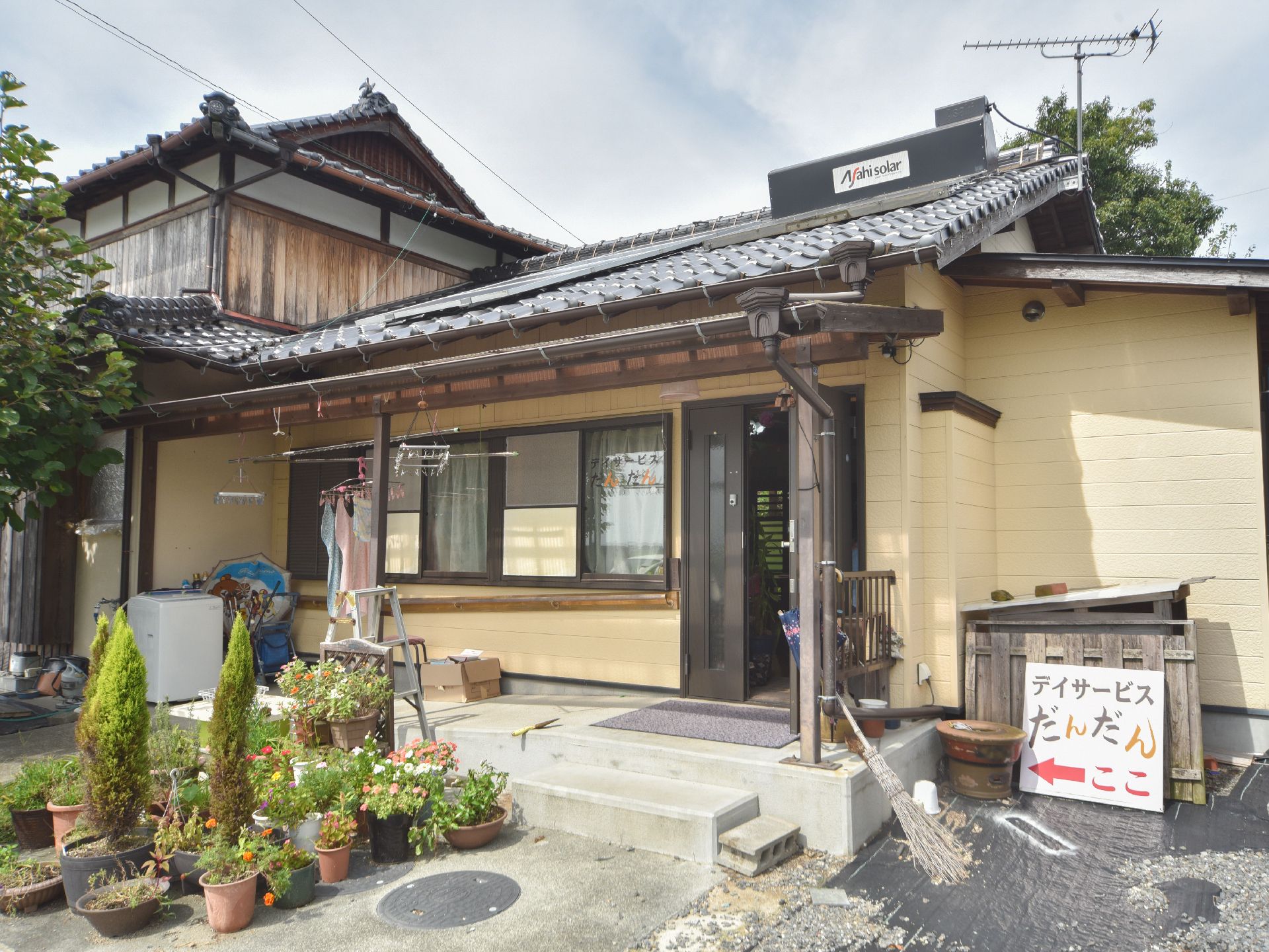 施設の入り口付近には様々な植物が植えられた鉢がたくさん置かれている。右側には施設名を表示したパネルが設置されている。