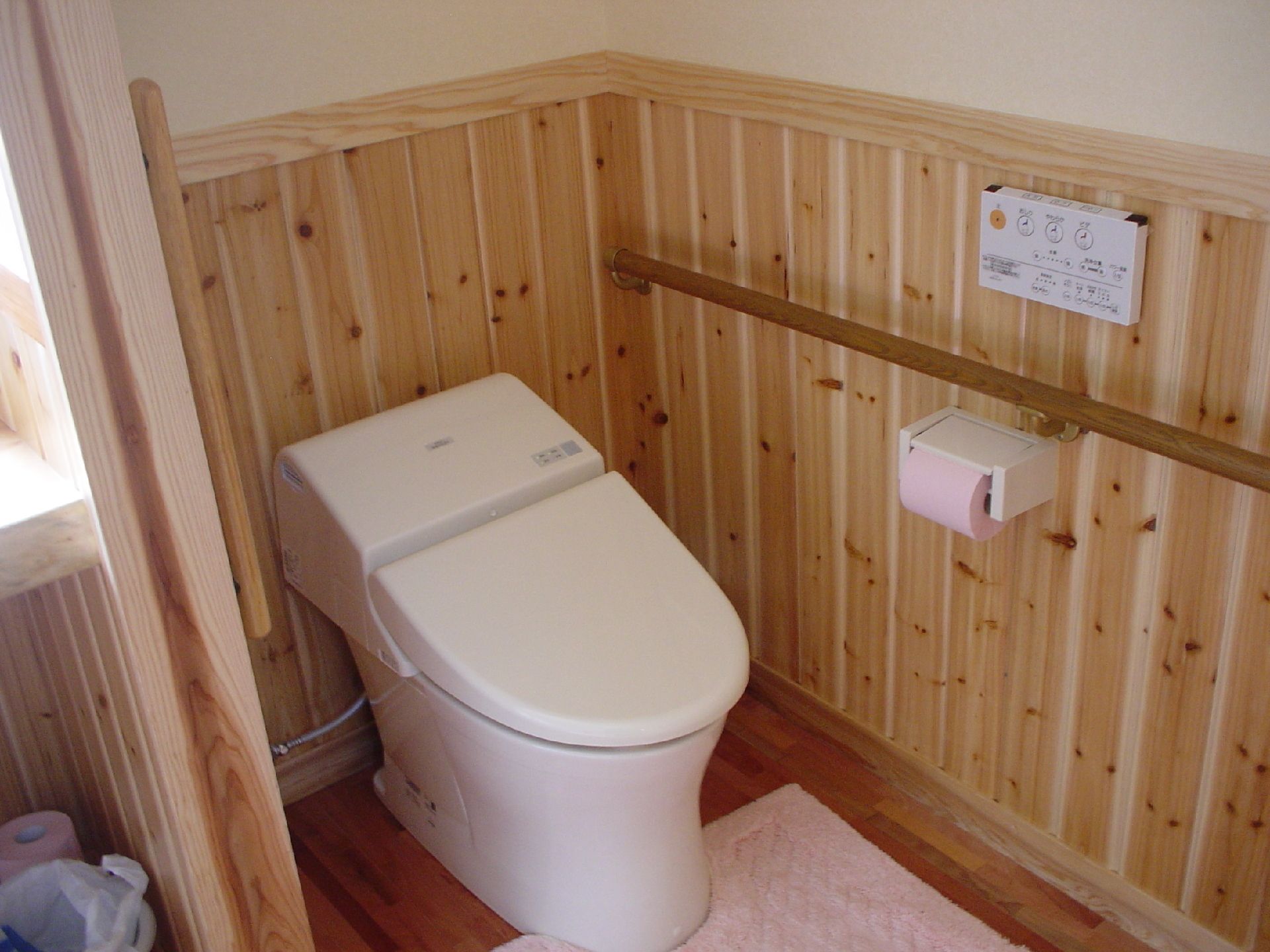 木目調の木のぬくもりを感じられるトイレである。温水洗浄便座を完備しており快適である。手すり付きなので安心して移動できる。