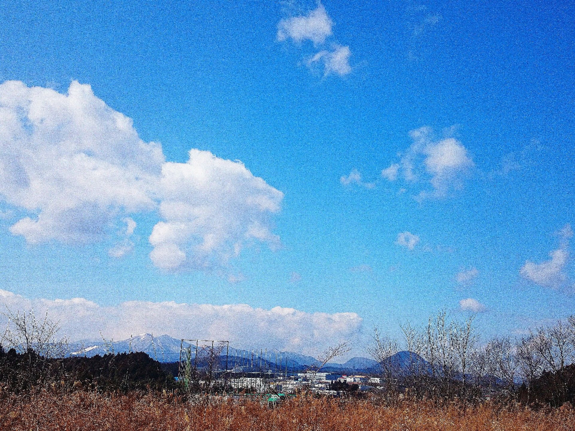 施設周辺の、遠くにいくつもの山が並ぶのどかな自然風景