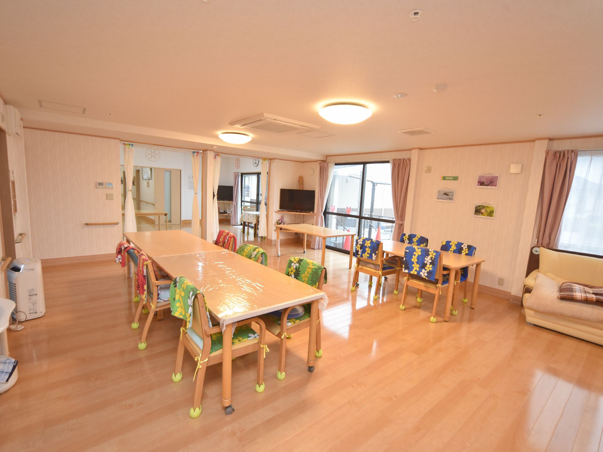 共有スペースの床は段差のないフローリングである。同系色の木製テーブルが置かれ、天板にはビニールクロスが掛けられている。