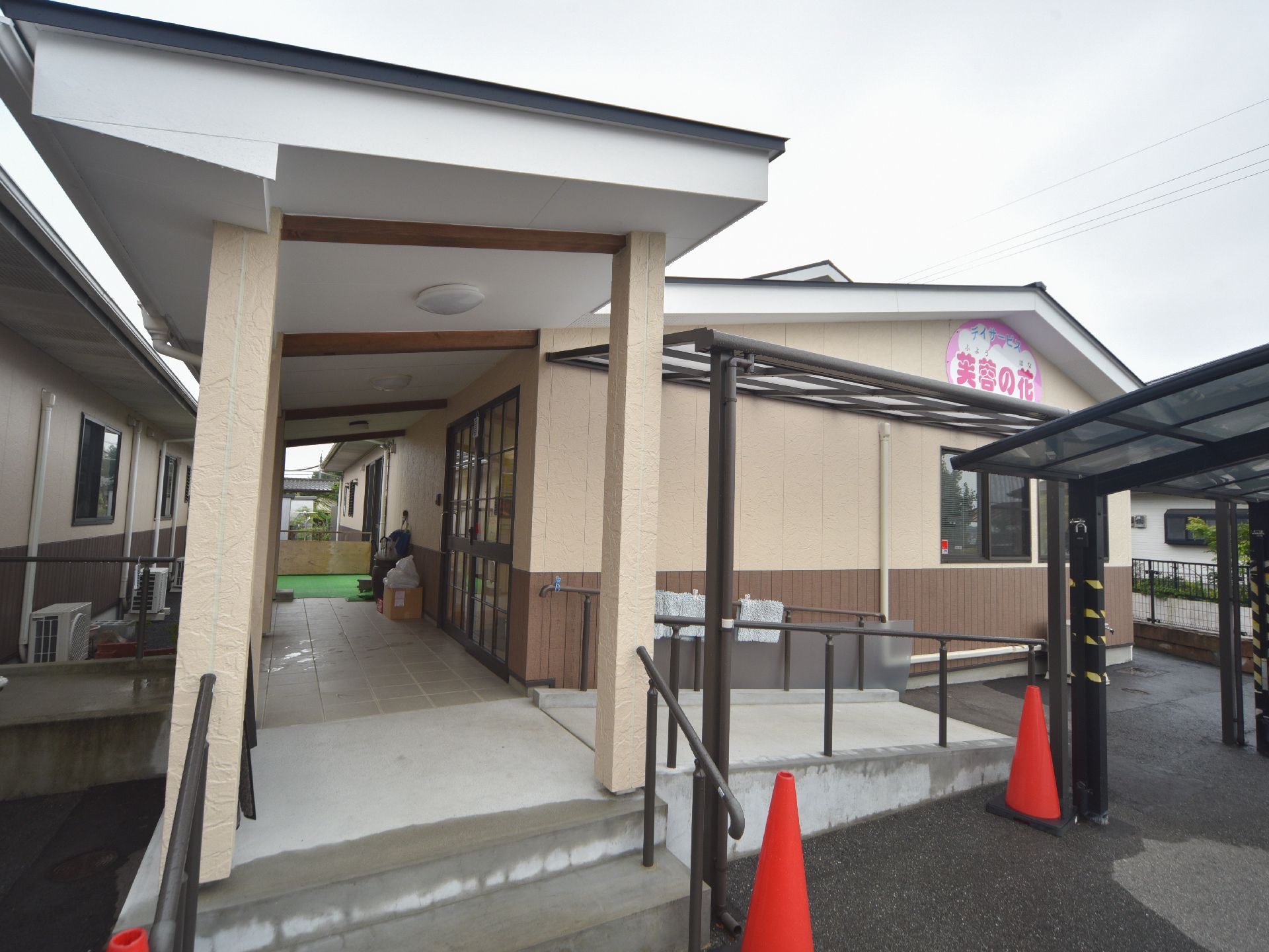 施設の入り口付近には2段のステップがあり、両脇には歩行をサポートする手すりが設置されている。右側にはスロープがある。
