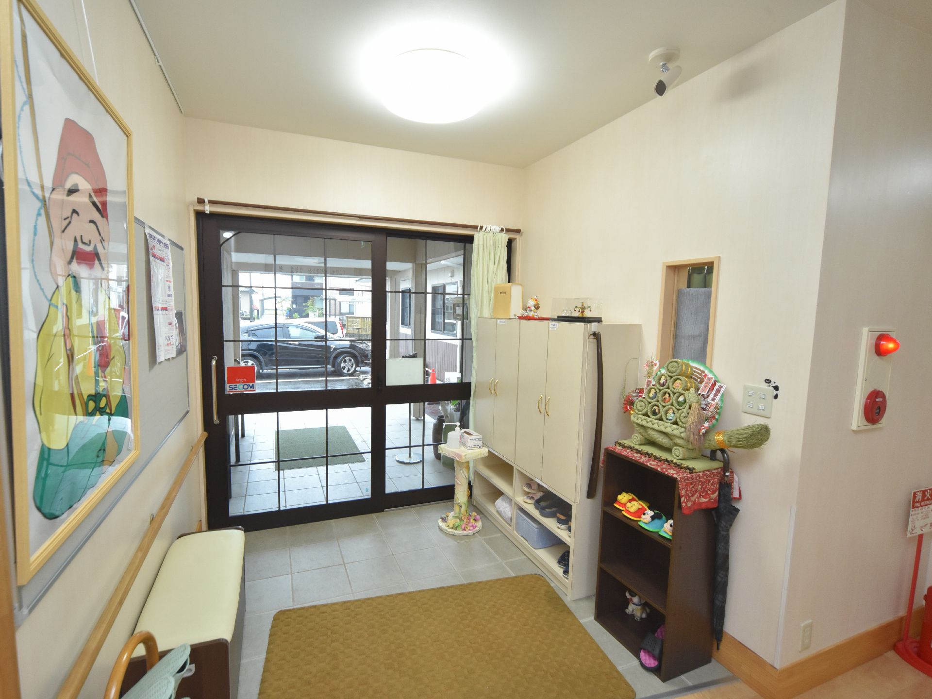 玄関ホールには右の壁際に白いシューズボックスが設置されている。右側にはスリッパ入れがあり、床にはマットが敷かれている。