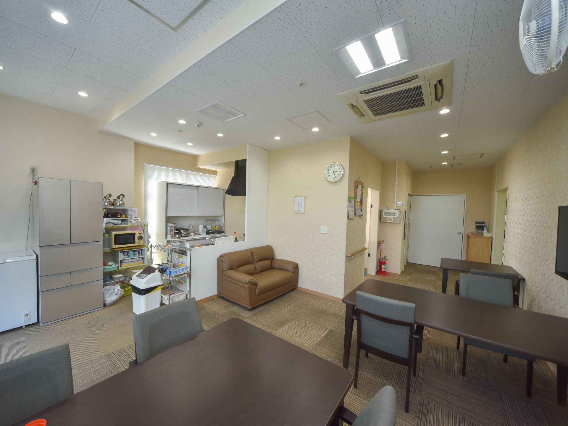 リビングダイニングにはキッチンが備わっており、大型冷蔵庫やゴミ箱が設置されている。4人掛けのダイニングテーブルセットが置かれている。