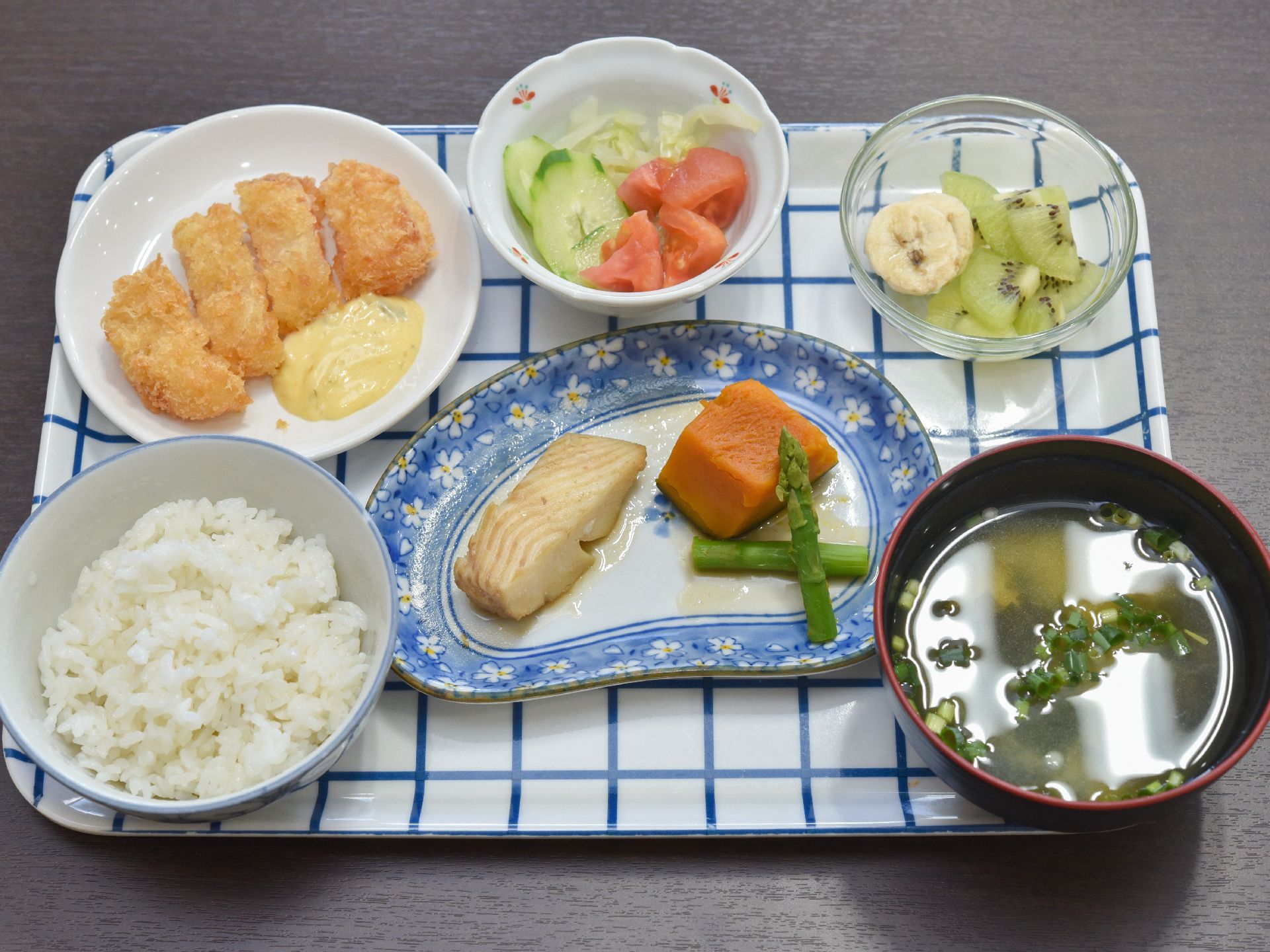 ご飯に味噌汁、白身魚と南瓜とアスパラの煮つけ、フライ、サラダに果物といった栄養のバランスの良い食事が出されている。