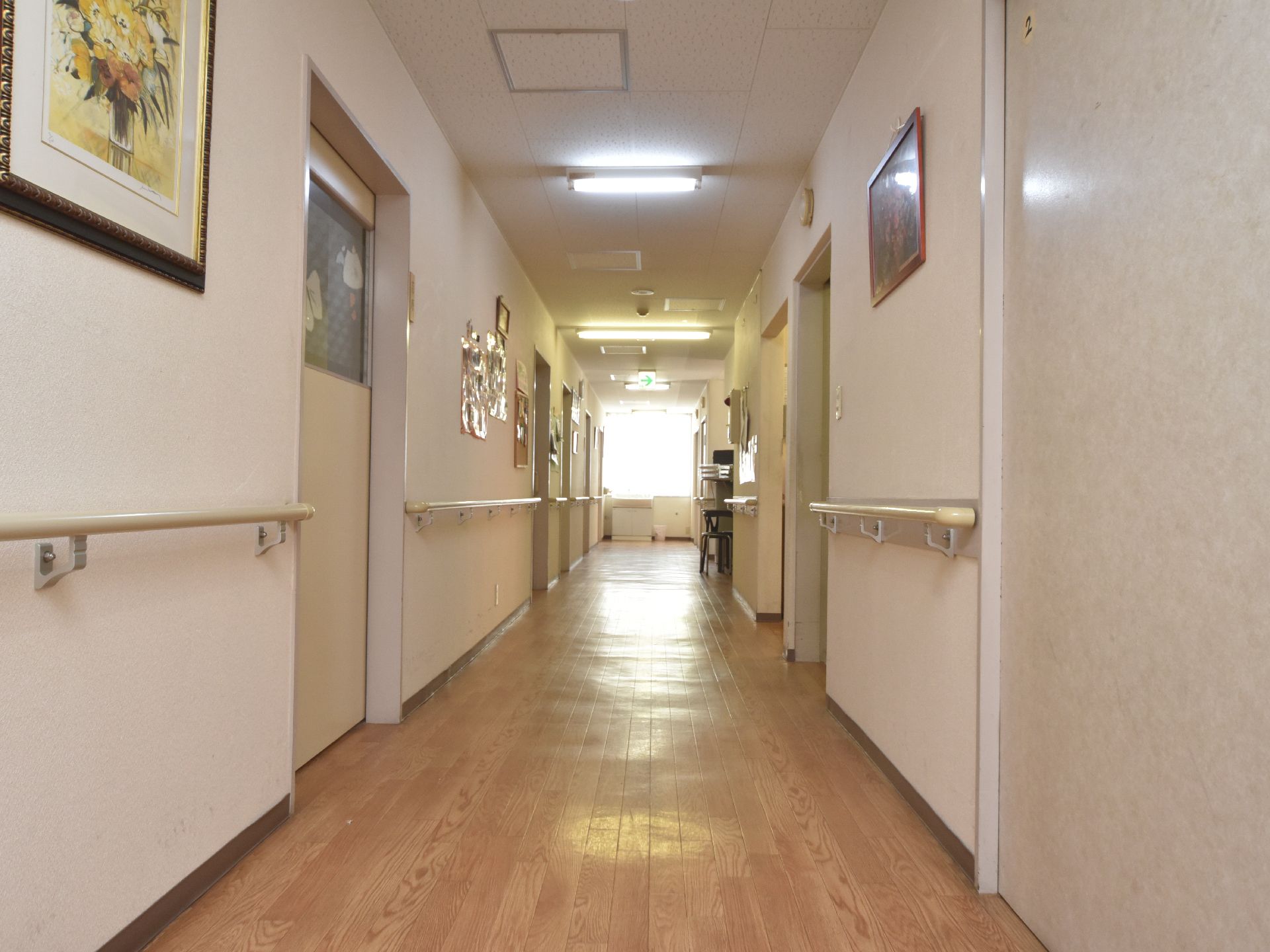 真っ直ぐな明るい廊下には、左右の壁に手すりが取り付けられており、絵が飾られている。車椅子が通れる広さもある。