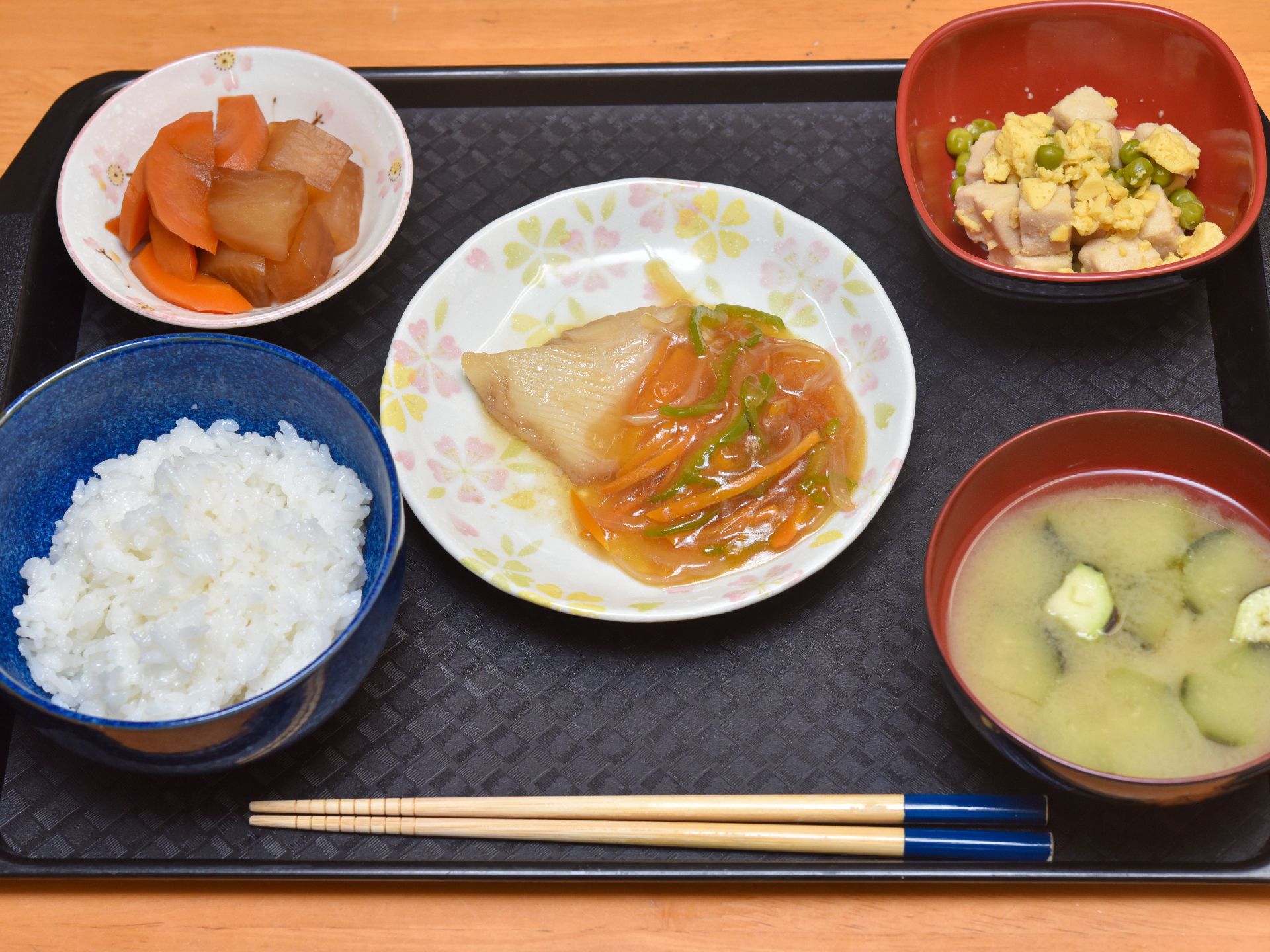 献立の一例をあげると、米飯、茄子の味噌汁、白身魚のあんかけ、大根と人参の煮物、高野豆腐と卵の炒め物である。