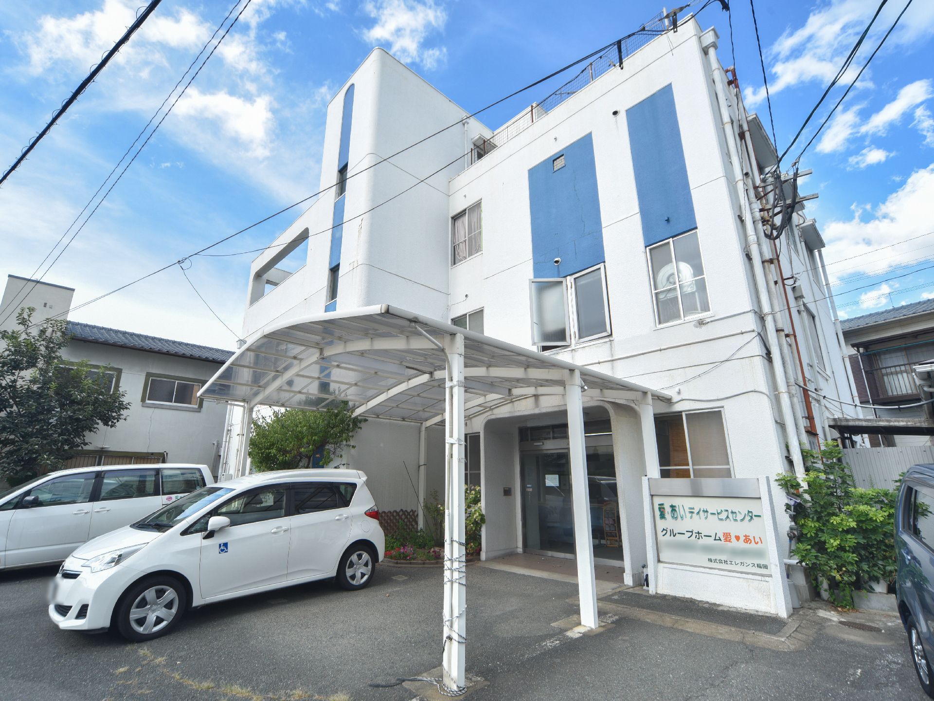 白い3階建の施設である。建物前には駐車場が確保されている。エントランスには雨除けの屋根が設置されている。